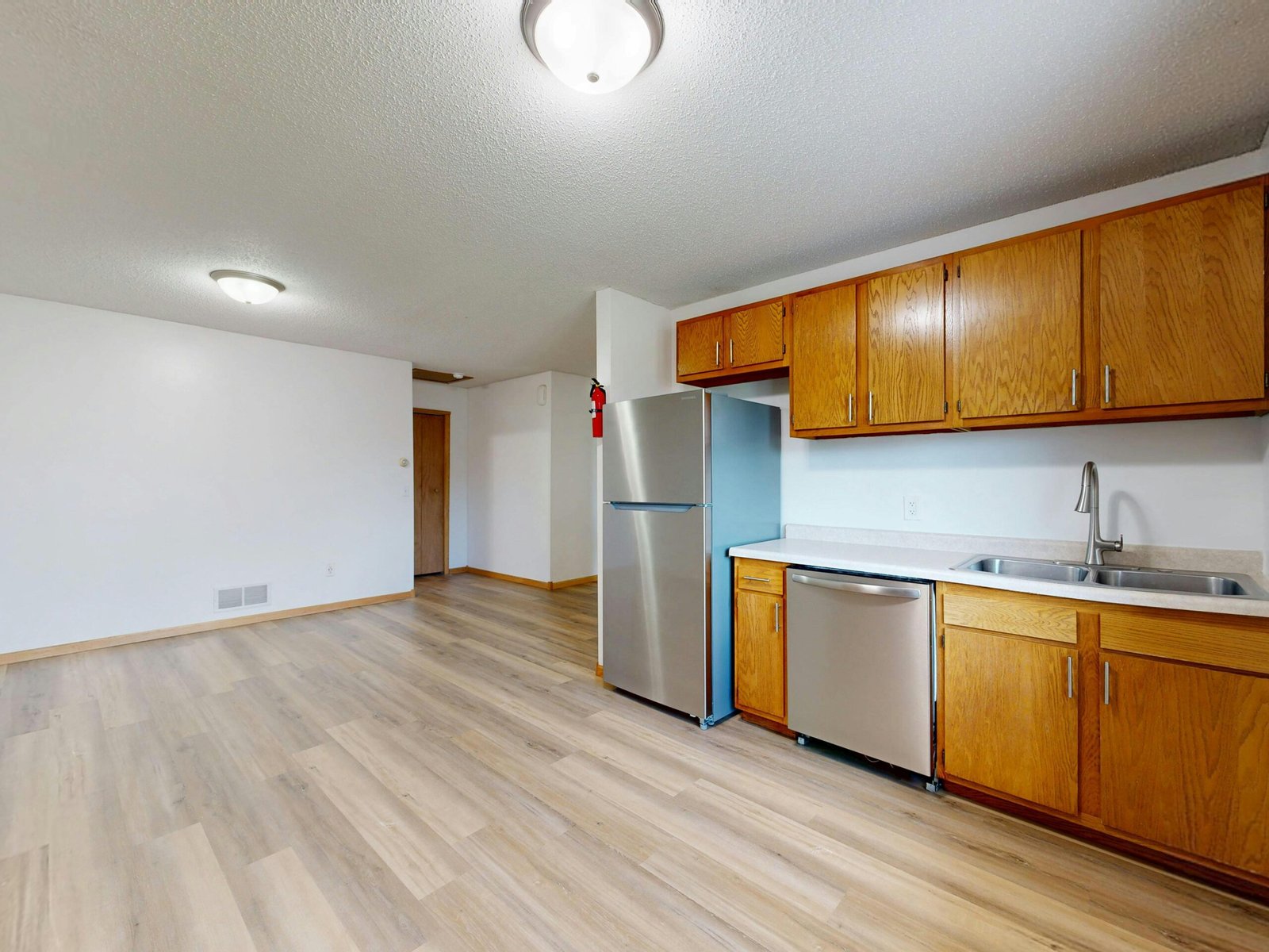 Spacious kitchen with wooden cabinets and floors, stainless steel appliances.
