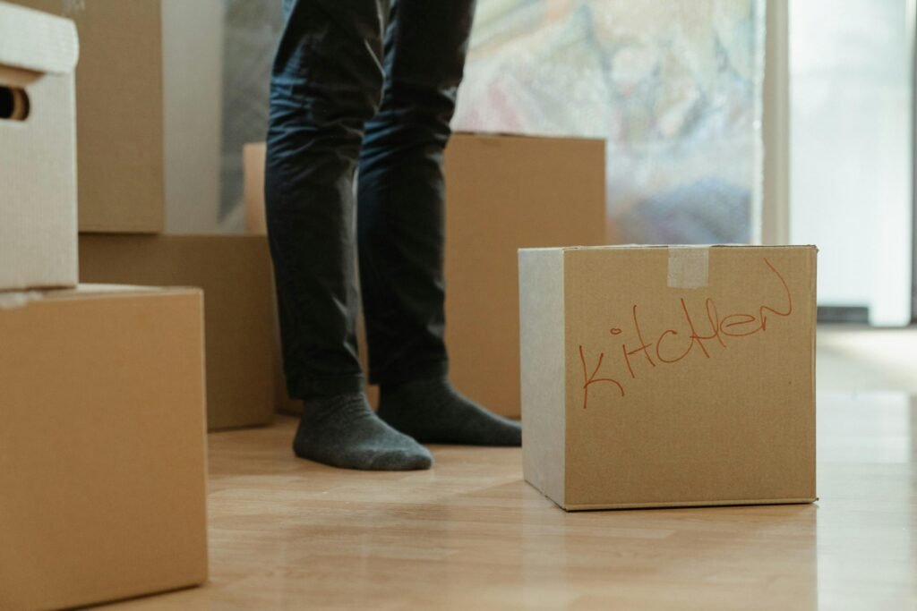 pjosfa-homes-moving company A man in a room surrounded by moving boxes labeled for the kitchen accessories.